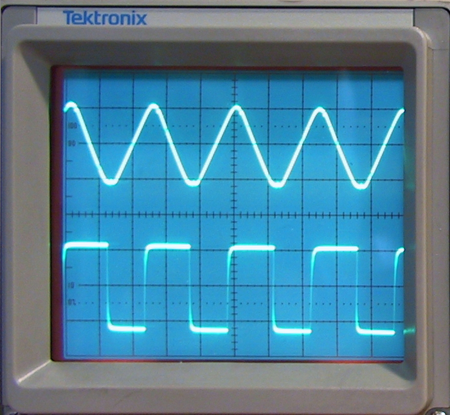 A triangle wave above a square wave on the screen of a Tektronix oscilloscope
